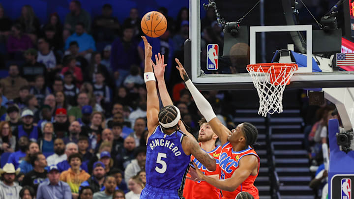 Feb 13, 2024; Orlando, Florida, USA; Orlando Magic forward Paolo Banchero (5) shoots the ball against Oklahoma City Thunder forward Jalen Williams (8) and forward Chet Holmgren (7) during the second half at Amway Center. Mandatory Credit: Mike Watters-Imagn Images