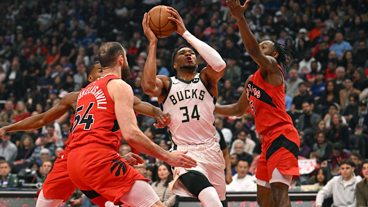 Oct 24, 2025; Toronto, Ontario, CAN; Milwaukee Bucks forward Giannis Antetokounmpo (34) is defended by Toronto Raptors forward Sandro Mamukelashvili (54) and guard Immanuel Quickley (5) in the first quarter at Scotiabank Arena. Mandatory Credit: Gerry Angus-Imagn Images