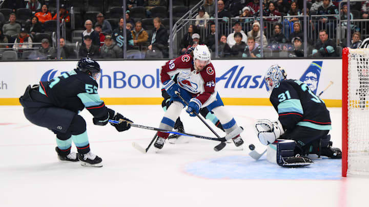 Dec 16, 2025; Seattle, Washington, USA; Colorado Avalanche defenseman Samuel Girard (49) plays the puck while defended by Seattle Kraken defenseman Ryan Lindgren (55) and Seattle Kraken goaltender Philipp Grubauer (31) during the third period at Climate Pledge Arena. Mandatory Credit: Steven Bisig-Imagn Images