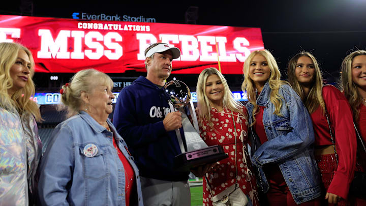 Mississippi Rebels head coach Lane Kiffin, center left, poses with the Ash Verlander Champions Trophy with his family after the game of the TaxSlayer Gator Bowl Thursday.