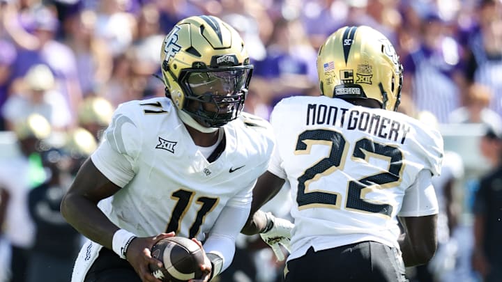 Sep 27, 2025; Manhattan, Kansas, USA; UCF Knights quarterback Jacurri Brown (11) fakes a handoff to running back Myles Montgomery (22) during the second quarter at Bill Snyder Family Football Stadium. Mandatory Credit: Scott Sewell-Imagn Images