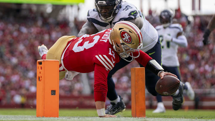 November 17, 2024; Santa Clara, California, USA; San Francisco 49ers quarterback Brock Purdy (13) scores a touchdown against Seattle Seahawks defensive tackle Jarran Reed (90) during the first quarter at Levi's Stadium. Mandatory Credit: Kyle Terada-Imagn Images