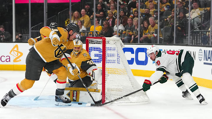 Apr 20, 2025; Las Vegas, Nevada, USA; Vegas Golden Knights goaltender Adin Hill (33) turns away a wrap-around attempt by Minnesota Wild left wing Marcus Johansson (90) as Vegas Golden Knights defenseman Brayden McNabb (3) looks to clear the puck during the first period of game one of the first round of the 2025 Stanley Cup Playoffs at T-Mobile Arena. Mandatory Credit: Stephen R. Sylvanie-Imagn Images