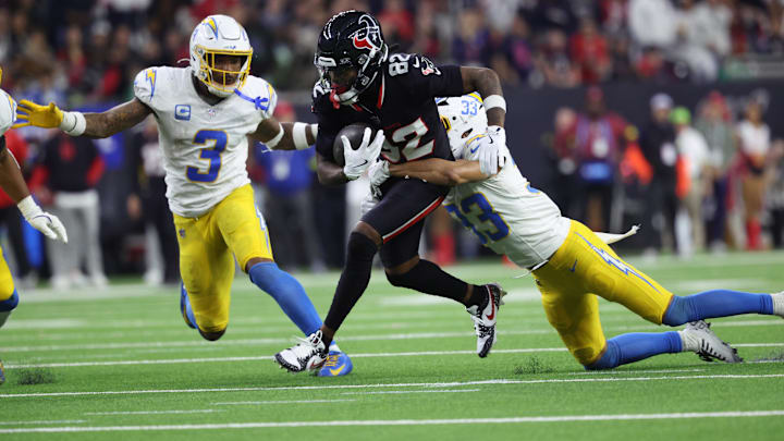 Jan 11, 2025; Houston, Texas, USA; Houston Texans wide receiver Diontae Johnson (82) runs the ball after a reception against Los Angeles Chargers defensive back Deane Leonard (33) and safety Derwin Jarnes Jr. (3) during the third quarter in an AFC wild card game at NRG Stadium.