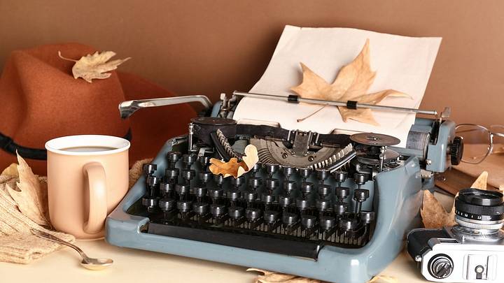 Typewriter with autumn leaves, film camera, and cup of coffee Typewriter with autumn leaves, film camera, and cup of coffee
