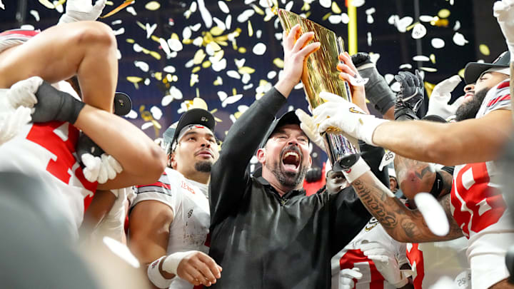 Ohio State coach Ryan Day holds up the national championship trophy as he celebrates with his team.