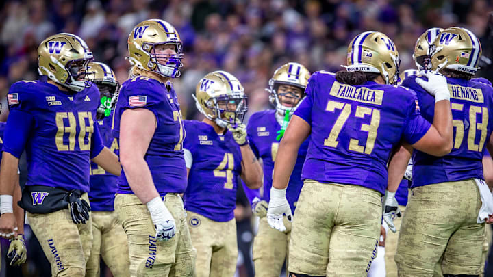 The Huskies huddle up, with freshmen John Mills (72) and Champ Taulealea (73) among those awaiting the next play.