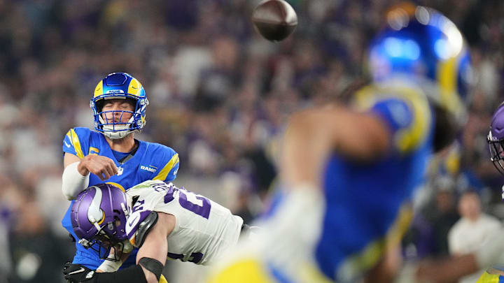 Los Angeles Rams quarterback Matthew Stafford (9) throws a touchdown pass to tight end Davis Allen (87) while being hit by Minnesota Vikings safety Harrison Smith (22) during their playoff game at State Farm Stadium on Jan. 13, 2025, in Glendale.