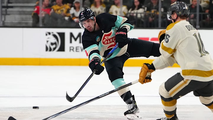 Mar 21, 2024; Las Vegas, Nevada, USA; Seattle Kraken defenseman Justin Schultz (4) dumps the puck over the stick of Vegas Golden Knights left wing Pavel Dorofeyev (16) during the third period at T-Mobile Arena. Mandatory Credit: Stephen R. Sylvanie-Imagn Images