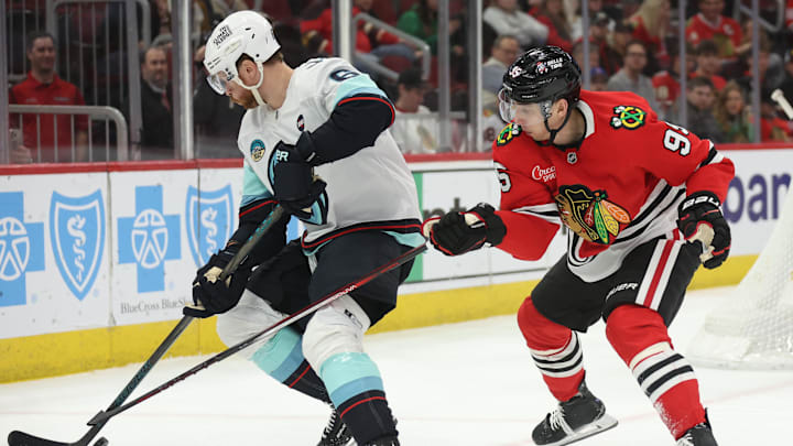 Mar 18, 2025; Chicago, Illinois, USA; Seattle Kraken defenseman Adam Larsson (6) and Chicago Blackhawks right wing Ilya Mikheyev (95) battle for control of the puck during the third period at United Center. Mandatory Credit: Talia Sprague-Imagn Images