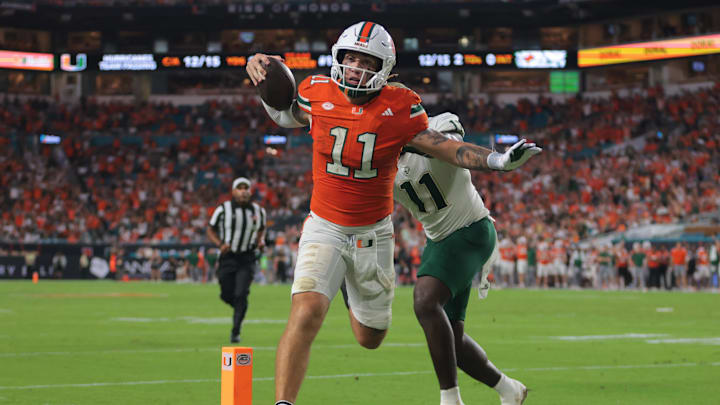 Sep 13, 2025; Miami Gardens, Florida, USA; Miami Hurricanes quarterback Carson Beck (11) carries the football for a touchdown against South Florida Bulls fullback D.J. Harris (11) during the second quarter at Hard Rock Stadium. Mandatory Credit: Sam Navarro-Imagn Images