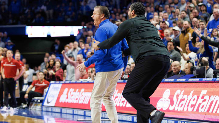 Kentucky Wildcats head coach John Calipari is held back by assistant Orlando Antigua against Arkansas last year. Both coach the Razorbacks now. Kentucky Wildcats head coach John Calipari is held back by assistant Orlando Antigua against Arkansas last year. Both coach the Razorbacks now.