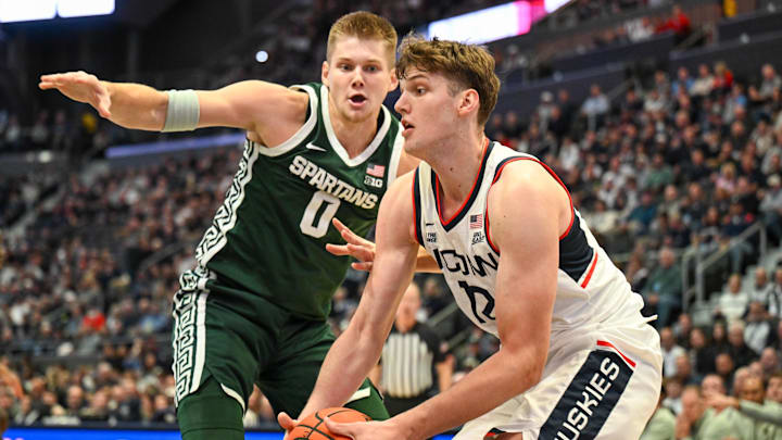 Oct 28, 2025; Hartford, CT, USA; Connecticut Huskies center Eric Reibe (12) controls the ball defended by Michigan State Spartans forward Jaxon Kohler (0) during the first half at PeoplesBank Arena. Mandatory Credit: Mark Smith-Imagn Images Oct 28, 2025; Hartford, CT, USA; Connecticut Huskies center Eric Reibe (12) controls the ball defended by Michigan State Spartans forward Jaxon Kohler (0) during the first half at PeoplesBank Arena. Mandatory Credit: Mark Smith-Imagn Images