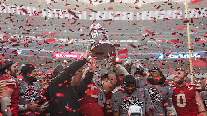 Dec 28, 2024; Bronx, NY, USA; Nebraska Cornhuskers head coach Matt Rhule holds the championship trophy as Cornhuskers players celebrate after the game against the Boston College Eagles at Yankee Stadium. Mandatory Credit: Vincent Carchietta-Imagn Images
