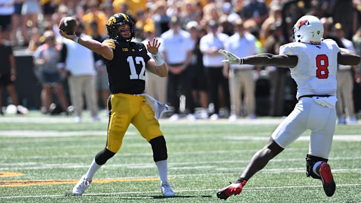 Aug 31, 2024; Iowa City, Iowa, USA; Iowa Hawkeyes quarterback Cade McNamara (12) throws a 31-yard touchdown pass as Illinois State Redbirds defensive lineman Steven Curtis (8) pursues during the third quarter at Kinnick Stadium. Mandatory Credit: Jeffrey Becker-USA TODAY Sports