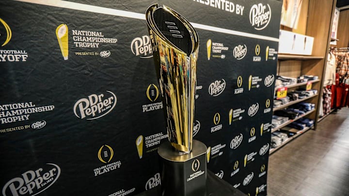 Fans stop to take photos with the College Football National Championship trophy.