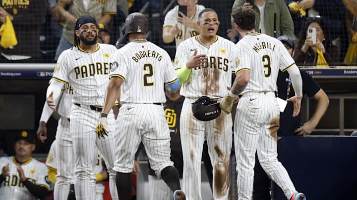 Oct 8, 2024; San Diego, California, USA; San Diego Padres second baseman Xander Bogaerts (2) and outfielder Jackson Merrill (3) celebrate with outfielder Fernando Tatis Jr. (23), left, and third baseman Manny Machado (13) after scoring in the second inning against the Los Angeles Dodgers during game three of the NLDS for the 2024 MLB Playoffs at Petco Park. Mandatory Credit: David Frerker-Imagn Images