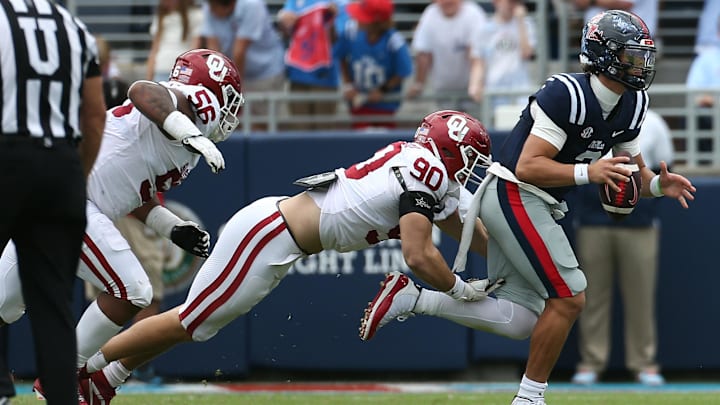 Ole Miss quarterback Jaxson Dart runs the ball as Oklahoma Sooners defensive lineman Caiden Woullard makes the tackle.