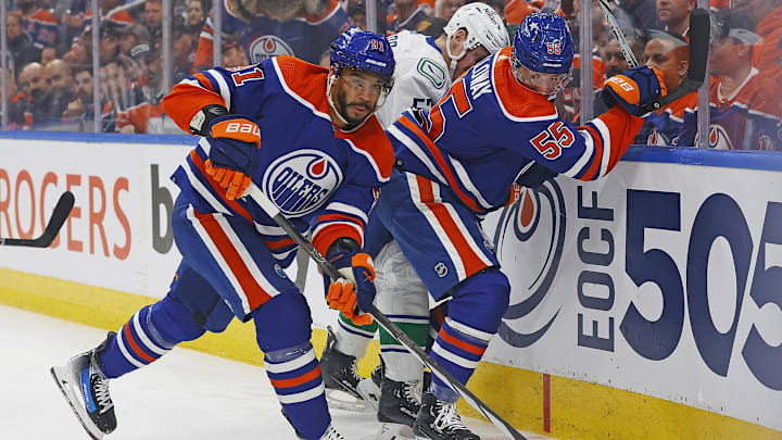 May 14, 2024; Edmonton, Alberta, CAN; Edmonton Oilers forward Evander Kane (91) clears a puck from a battle between forward Dylan Holloway (55) and Vancouver Canucks forward Teddy Blueger (53) during the first period in game four of the second round of the 2024 Stanley Cup Playoffs at Rogers Place. Mandatory Credit: Perry Nelson-Imagn Images