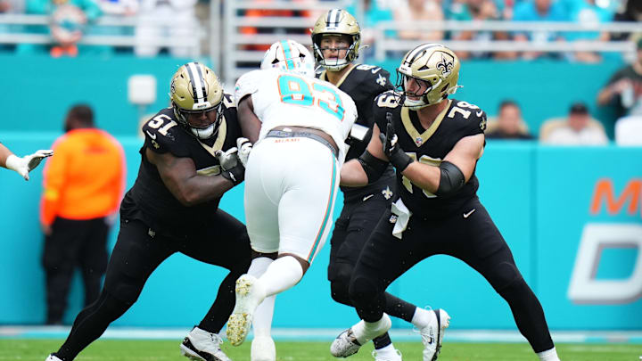 Nov 30, 2025; Miami Gardens, Florida, USA; New Orleans Saints center Cesar Ruiz (51) and center Luke Fortner (79) attempt to block Miami Dolphins defensive tackle Zeek Biggers (93) during the first half at Hard Rock Stadium. Mandatory Credit: Rich Storry-Imagn Images