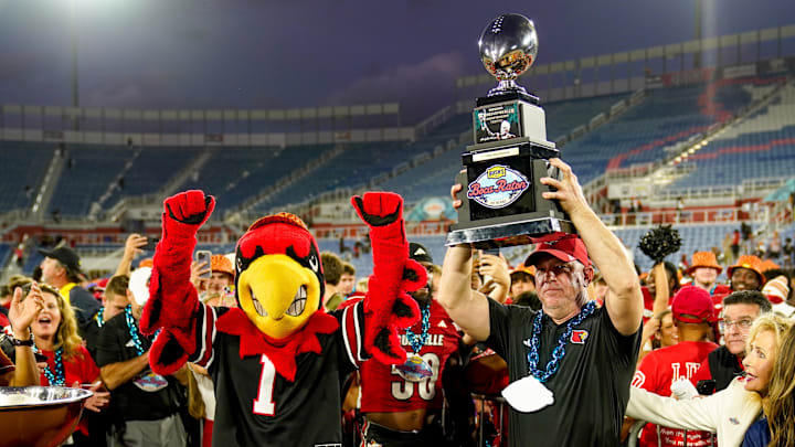 Dec 23, 2025; Boca Raton, FL, USA; Louisville Cardinals head coach Jeff Brohm raises the trophy after defeating the Toledo Rockets in the Boca Raton Bowl at Flagler CU Stadium. Mandatory Credit: Jeff Romance-Imagn Images