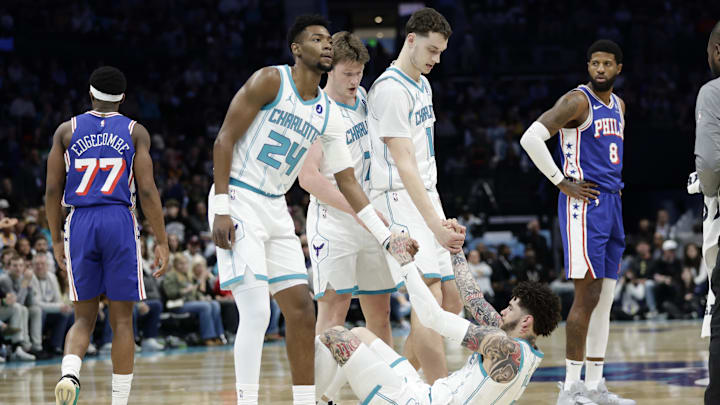 Charlotte Hornets guard LaMelo Ball (1) is helped up off the floor by teammates 