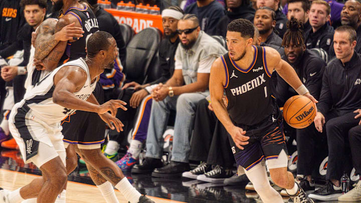 Nov 2, 2025; Phoenix, Arizona, USA; Phoenix Suns guard Devin Booker (1) drives against San Antonio Spurs forward Harrison Barnes (40) during the first half at PHX Arena. Mandatory Credit: Allan Henry-Imagn Images