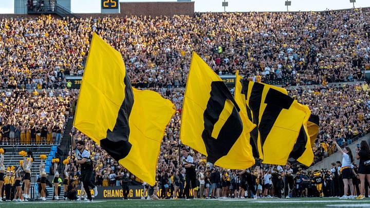 Iowa cheerleaders carry flags spelling Iowa across the field ahead of the Cy-Hawk football game Sept. 12, 2026 at Kinnick Stadium in Iowa City, Iowa.
