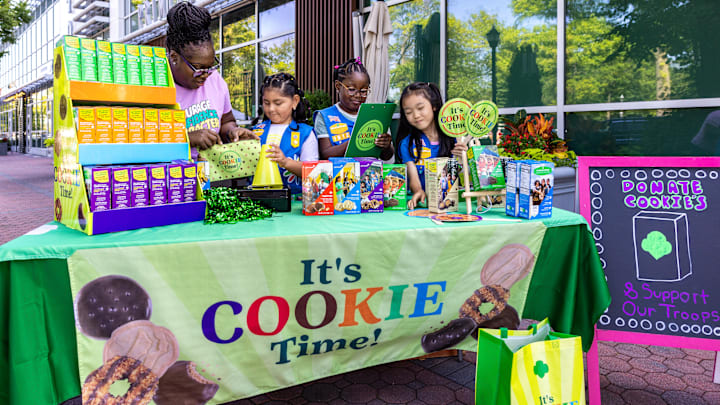 Daisy Girl Scouts and a leader selling at a cookie booth.