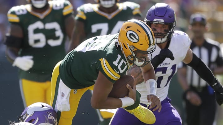 Green Bay Packers quarterback Jordan Love is tackled by Minnesota Vikings linebacker Andrew Van Ginkel.