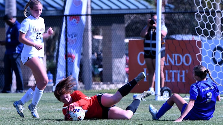 Cypress Bay junior McKenzie Rector goes to the ground with the Lake Mary goalkeeper after she unleashed a hard shot during the closing minutes of the FHSAA Class 7A girls soccer state championship game at Lake Myrtle Sports Complex on Friday.