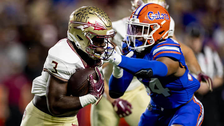 Florida State Seminoles running back Trey Benson (3) rushes with the ball while Florida Gators linebacker Mannie Nunnery (34) attempts to tackle during the first half at Steve Spurrier Field at Ben Hill Griffin Stadium in Gainesville, FL on Saturday, November 25, 2023. [Matt Pendleton/Gainesville Sun]
