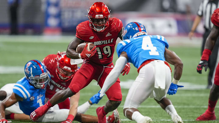 Sep 6, 2021; Atlanta, Georgia, USA; Louisville Cardinals running back Hassan Hall (19) runs the ball against Mississippi Rebels defensive back Tylan Knight (4) during the first quarter at Mercedes-Benz Stadium. Mandatory Credit: Dale Zanine-Imagn Images Sep 6, 2021; Atlanta, Georgia, USA; Louisville Cardinals running back Hassan Hall (19) runs the ball against Mississippi Rebels defensive back Tylan Knight (4) during the first quarter at Mercedes-Benz Stadium. Mandatory Credit: Dale Zanine-Imagn Images
