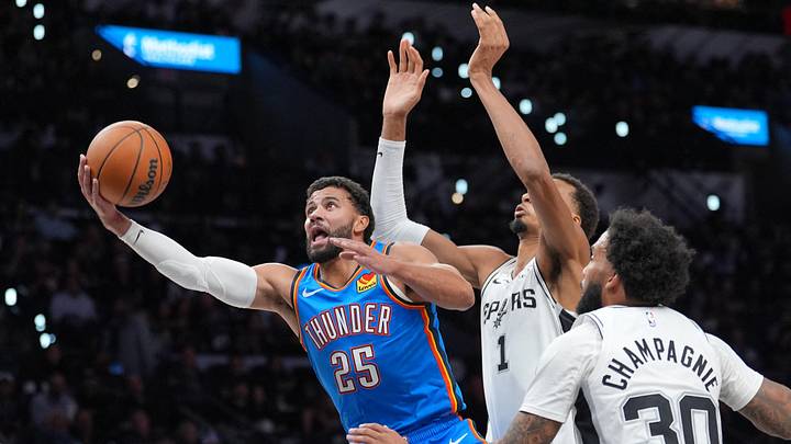 Oct 20, 2026; San Antonio, Texas, USA;  Oklahoma City Thunder guard Ajay Mitchell (25) shoots in front of San Antonio Spurs forwards Victor Wembanyama (1) and Julian Champagnie (30) in the first half at Frost Bank Center.  Mandatory Credit: Daniel Dunn-Imagn Images