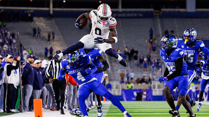 Oct 26, 2024; Lexington, Kentucky, USA; Auburn Tigers running back Damari Alston (0) hurdles Kentucky Wildcats defensive back Kristian Story (4) during the fourth quarter at Kroger Field. Mandatory Credit: Jordan Prather-Imagn Images