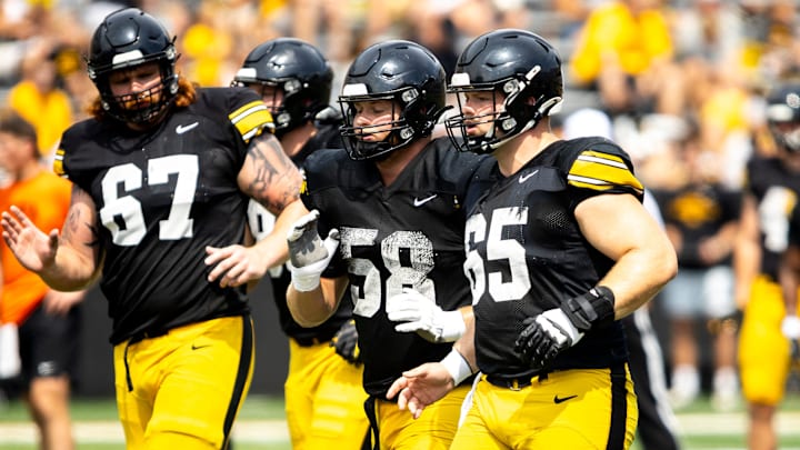 Aug 9, 2025; Iowa offensive linemen Gennings Dunker (67) Kade Pieper (58) and Logan Jones (65) run a drill during the Hawkeyes Kids Day NCAA football open practice at Kinnick Stadium in Iowa City, Iowa. Mandatory Credit: Joseph Cress for the Des Moines Register