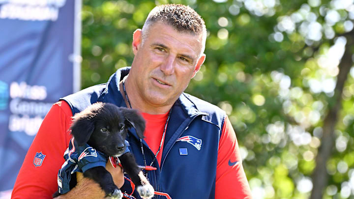 Jul 23, 2025; Foxborough, MA, USA; New England Patriots head coach Mike Vrabel delivers a puppy to a local family before addressing the media during training camp at Gillette Stadium. Mandatory Credit: Eric Canha-Imagn Images
