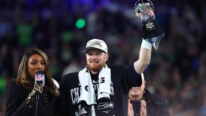 Feb 8, 2026; Santa Clara, CA, USA; Seattle Seahawks quarterback Sam Darnold (14) celebrates with the Vince Lombardi trophy on the podium after defeating the New England Patriots in Super Bowl LX at Levi's Stadium. Mandatory Credit: Mark J. Rebilas-Imagn Images