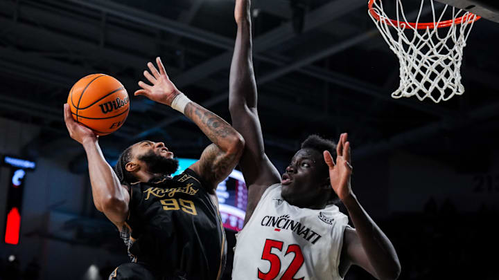 Feb 8, 2026; Cincinnati, Ohio, USA;  UCF Knights forward Jordan Burks (99) drives to the basket as he is fouled by Cincinnati Bearcats center Moustapha Thiam (52) in the second half at Fifth Third Arena. Mandatory Credit: Aaron Doster-Imagn Images