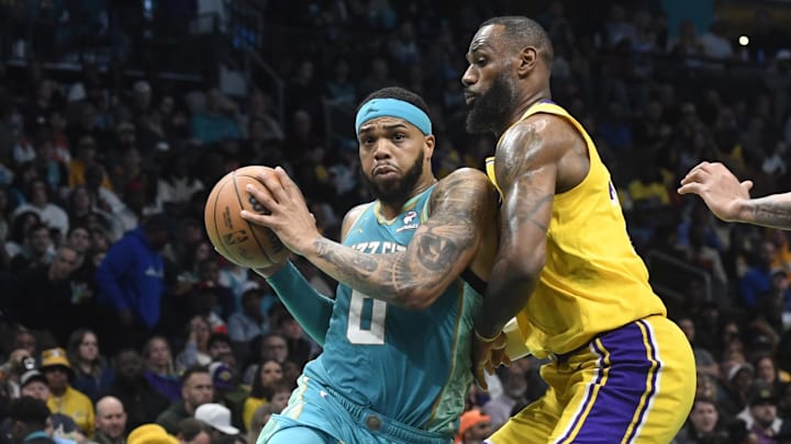 Feb 5, 2024; Charlotte, North Carolina, USA;  Charlotte Hornets forward Miles Bridges (0) drives past Los Angeles Lakers forward LeBron James (23) during the second half at the Spectrum Center. Mandatory Credit: Sam Sharpe-Imagn Images