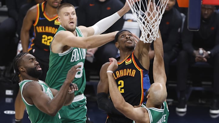 Jan 5, 2025; Oklahoma City, Oklahoma, USA; Oklahoma City Thunder guard Shai Gilgeous-Alexander (2) shoots the ball against Boston Celtics center Kristaps Porzingis (8) and guard Derrick White (9) during the first quarter at Paycom Center. Mandatory Credit: Alonzo Adams-Imagn Images