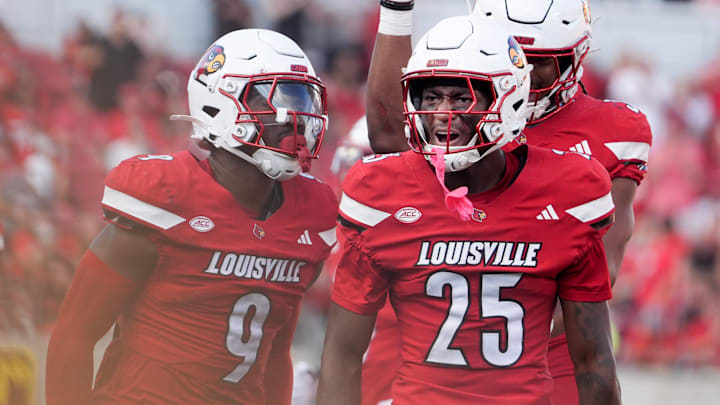 Louisville’s Tayon Holloway (#25) celebrates with Antonio Watts the sacking of Virginia’s J’Mari Taylor at L&N Stadium Saturday.