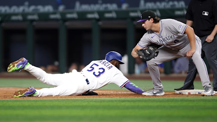 May 14, 2025; Arlington, Texas, USA; Texas Rangers outfielder Adolis García (53) dives back to first base as Colorado Rockies first base Michael Toglia (4) attempts to make the tag during the third inning at Globe Life Field. Mandatory Credit: Tim Heitman-Imagn Images