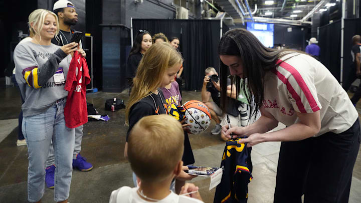 Fever guard Caitlin Clark signs autographs as ASU women's basketball head coach Molly Miller takes photos of her children Crosby and Cy at PHX Arena in Phoenix on Aug. 7, 2025.