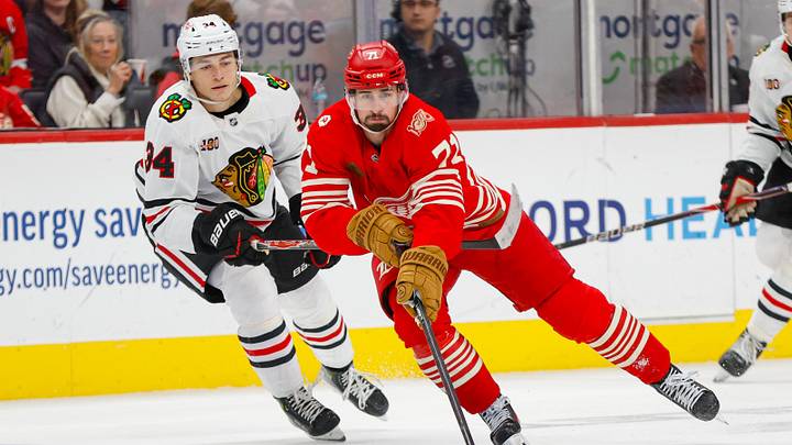 Nov 9, 2025; Detroit, Michigan, USA; Detroit Red Wings center Dylan Larkin (71) handles the puck against Chicago Blackhawks center Colton Dach (34) during the second period at Little Caesars Arena. Mandatory Credit: Brian Bradshaw Sevald-Imagn Images