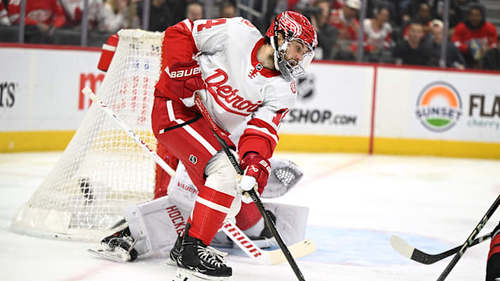 Mar 4, 2025; Detroit, Michigan, USA;  Detroit Red Wings center Tyler Motte (14) clears the puck from in front of their goal against the Carolina Hurricanes in the first period at Little Caesars Arena. Mandatory Credit: Lon Horwedel-Imagn Images