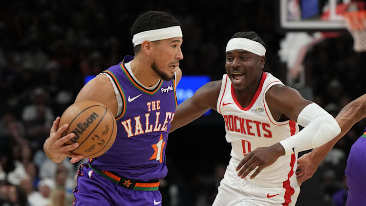 Mar 30, 2025; Phoenix, Arizona, USA; Phoenix Suns guard Devin Booker (1) drives on Houston Rockets guard Aaron Holiday (0) in the first half at Footprint Center. Mandatory Credit: Rick Scuteri-Imagn Images