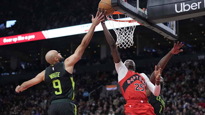 Jan 15, 2025; Toronto, Ontario, CAN; Toronto Raptors forward Chris Boucher (25) shoots against Boston Celtics guard Derrick White (9) and forward Jaylen Brown (7) during the second half at Scotiabank Arena. Mandatory Credit: John E. Sokolowski-Imagn Images