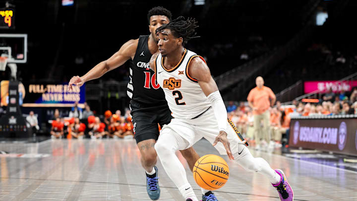 Mar 11, 2025; Kansas City, MO, USA; Oklahoma State Cowboys guard Arturo Dean (2) drives to the basket around Cincinnati Bearcats guard Josh Reed (10) during the first half at T-Mobile Center. Mandatory Credit: William Purnell-Imagn Images Mar 11, 2025; Kansas City, MO, USA; Oklahoma State Cowboys guard Arturo Dean (2) drives to the basket around Cincinnati Bearcats guard Josh Reed (10) during the first half at T-Mobile Center. Mandatory Credit: William Purnell-Imagn Images