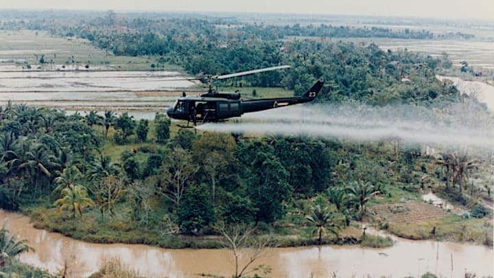 An American Huey helicopter sprays Agent Orange over Vietnam.